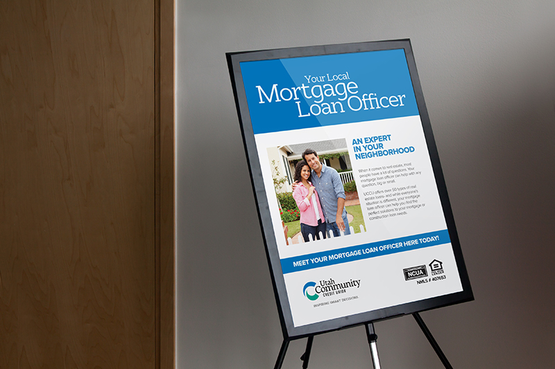 poster in frame advertising local mortgage loan officer with couple proudly showing keys to new house